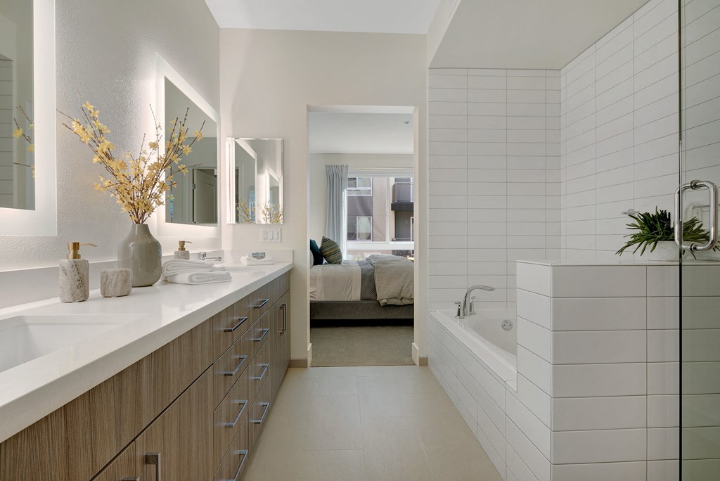 a bathroom with two sinks and a tub and a bedroom