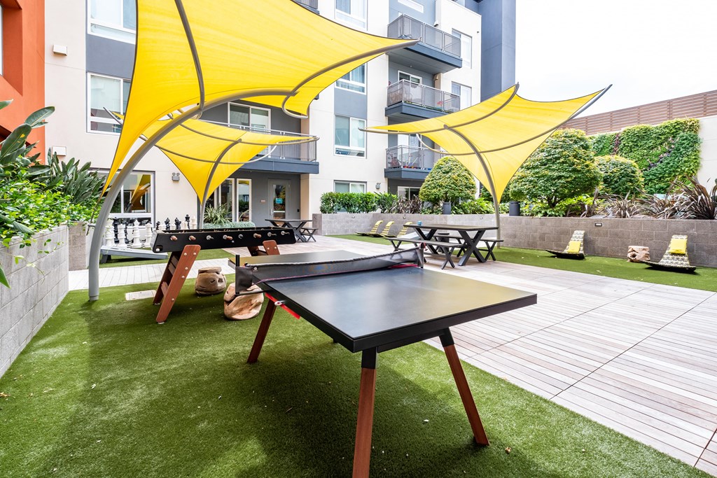 a patio with a ping pong table and umbrellas