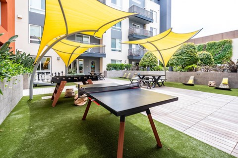 a patio with a ping pong table and umbrellas