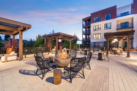 a patio with tables and chairs and a fire pit