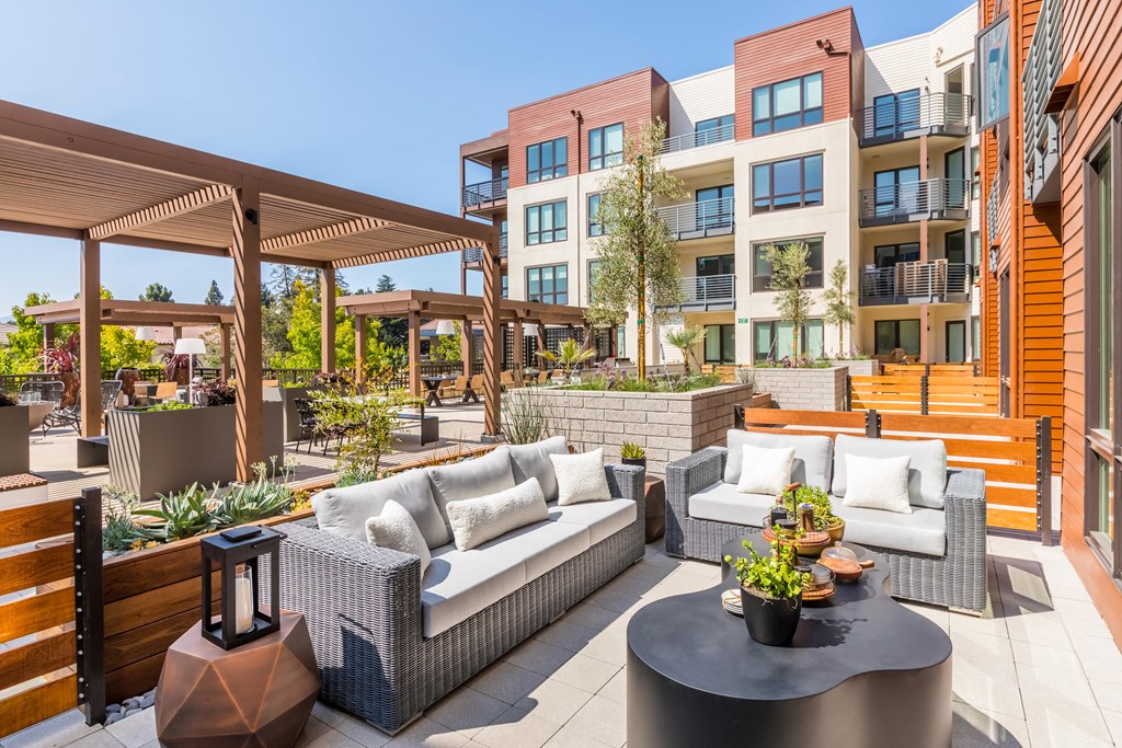 a patio with couches and a table in front of an apartment building
