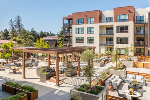 a rendering of a patio area with tables and chairs in front of an apartment building