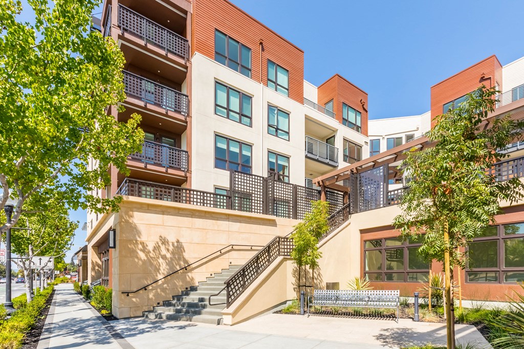 an apartment building with stairs and trees in front of it