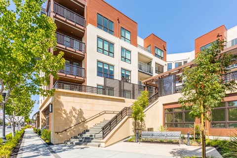 an apartment building with stairs and trees in front of it
