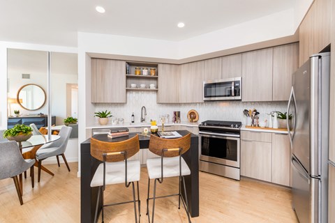 a kitchen with stainless steel appliances and a island with three chairs