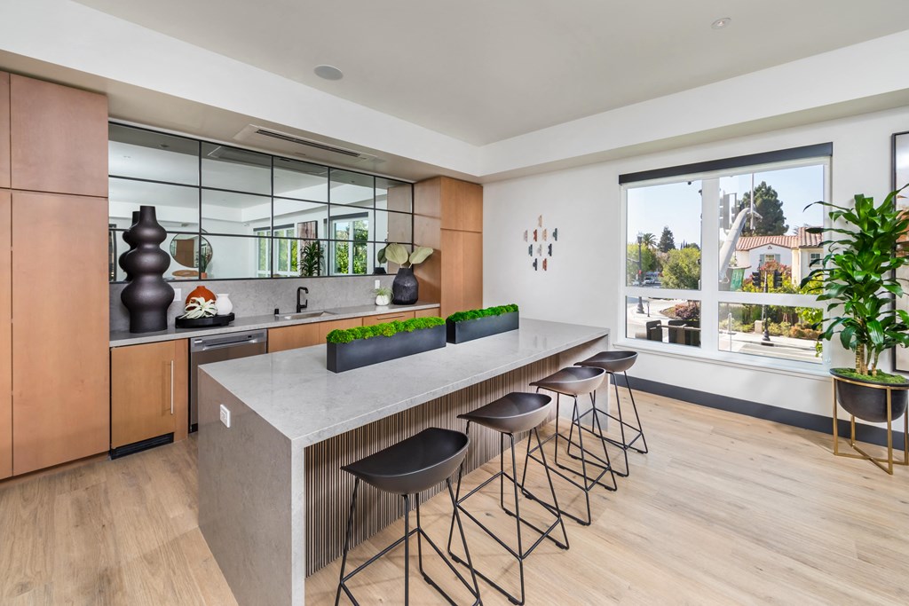 a kitchen with an island and stools in front of a large window