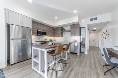 A modern kitchen with a stainless steel refrigerator and a dining table with chairs.