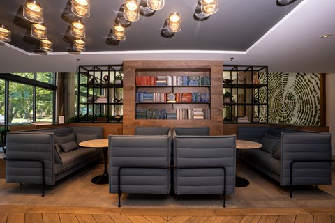 A modern lounge area with grey couches and a bookshelf filled with books.