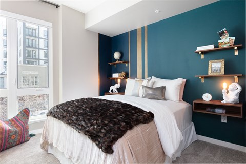 a bedroom with a bed and a blue wall and a window