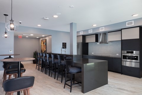 a kitchen with a long counter and chairs in front of a bar with stools
