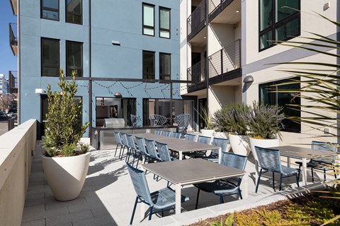 an outdoor patio with tables and chairs in front of a building