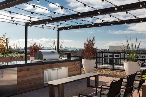 a rooftop patio with a grill and a table with chairs