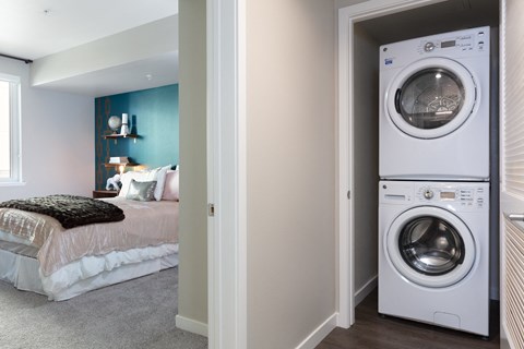a bedroom with a washer and dryer and a bed