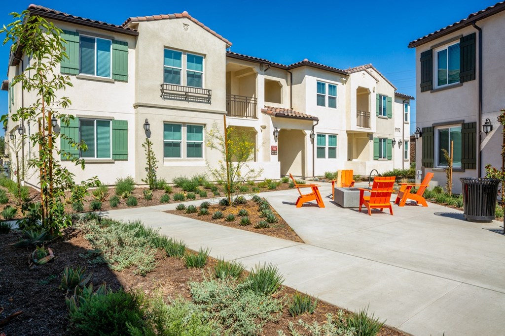 a group of apartments with a patio with orange chairs