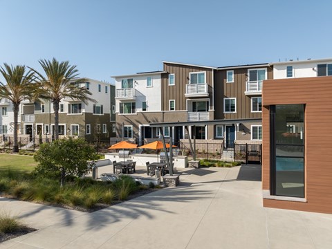 A modern apartment complex with a courtyard and palm trees.