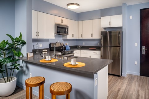 A kitchen with a grey counter top and white cabinets.