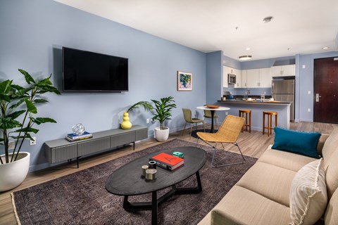 A living room with a couch, a coffee table, and a television mounted on the wall.