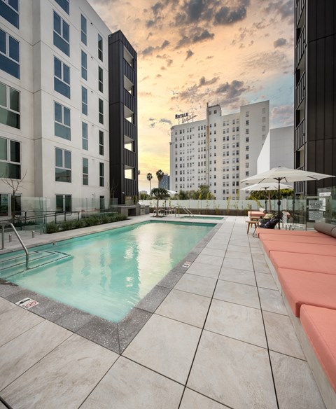 A swimming pool surrounded by buildings and lounging areas.