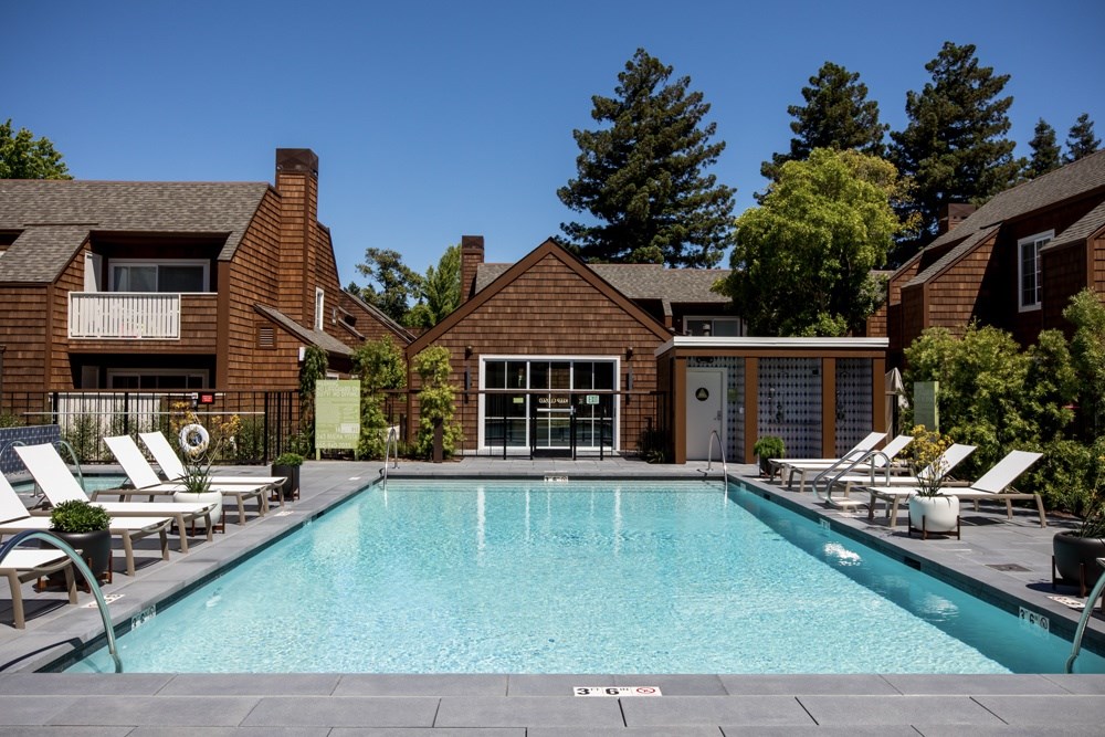A swimming pool surrounded by lounge chairs and buildings.