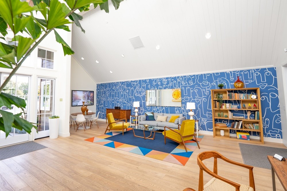 A living room with a blue patterned wallpaper and a variety of furniture.