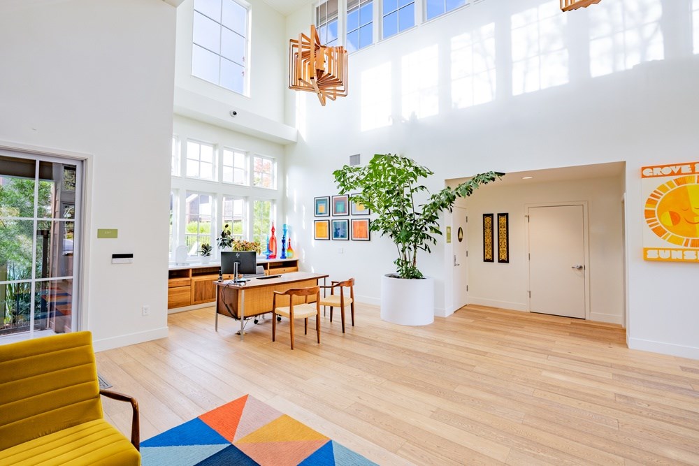 A brightly lit room with a yellow chair and a colorful rug.