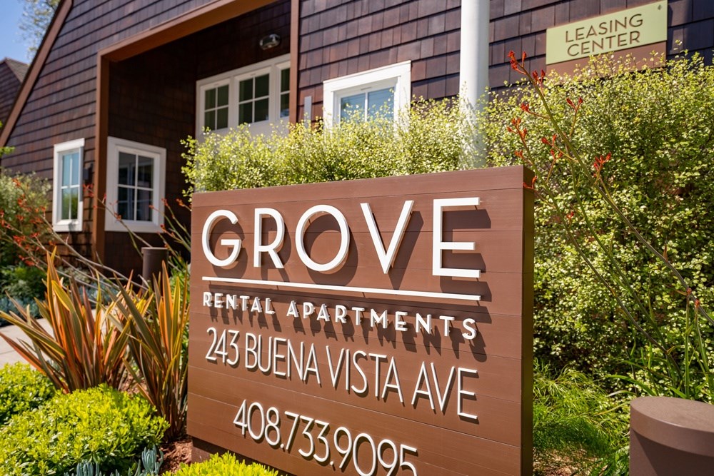 A sign for Grove Rental Apartments is displayed in front of a building.
