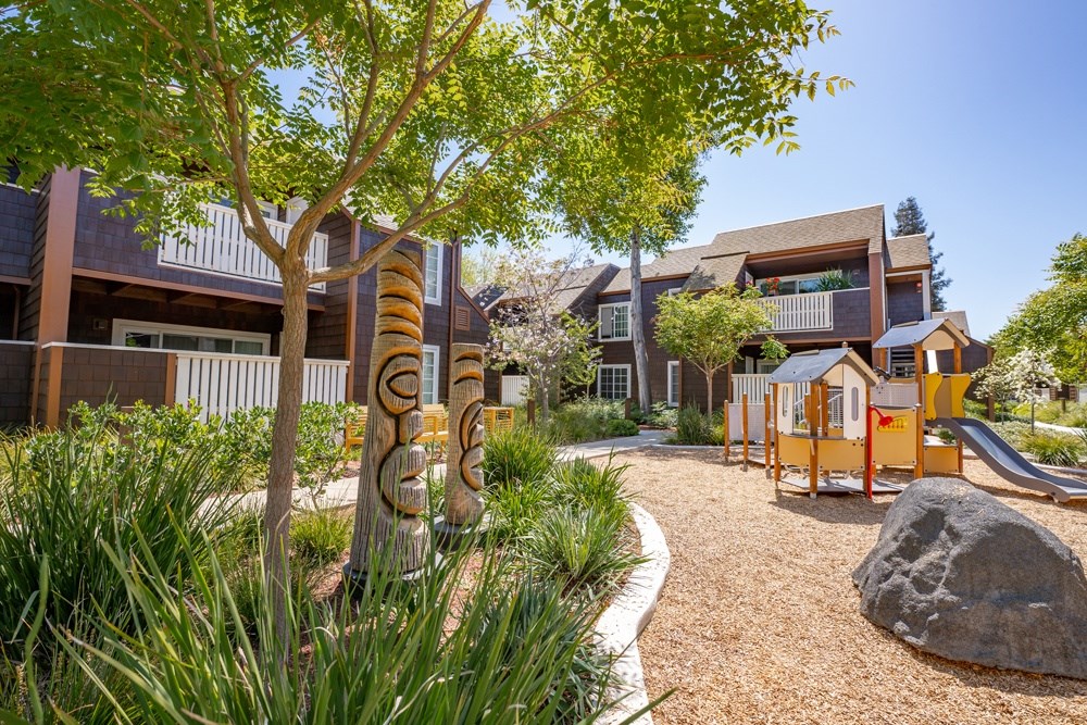 A playground area with a slide and a rock in the foreground.