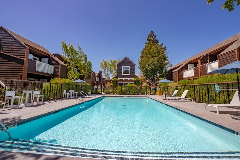 A large swimming pool surrounded by lounge chairs and buildings.