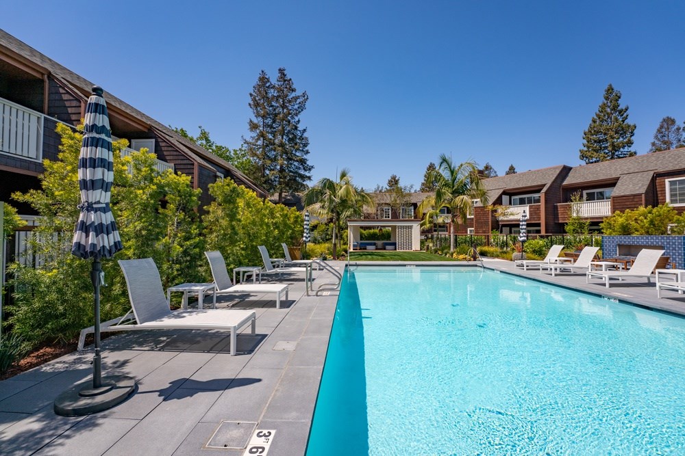 A pool surrounded by chairs and umbrellas.