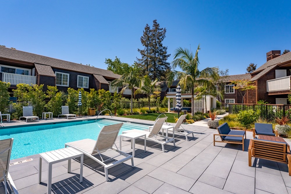 A poolside area with chairs and a table.