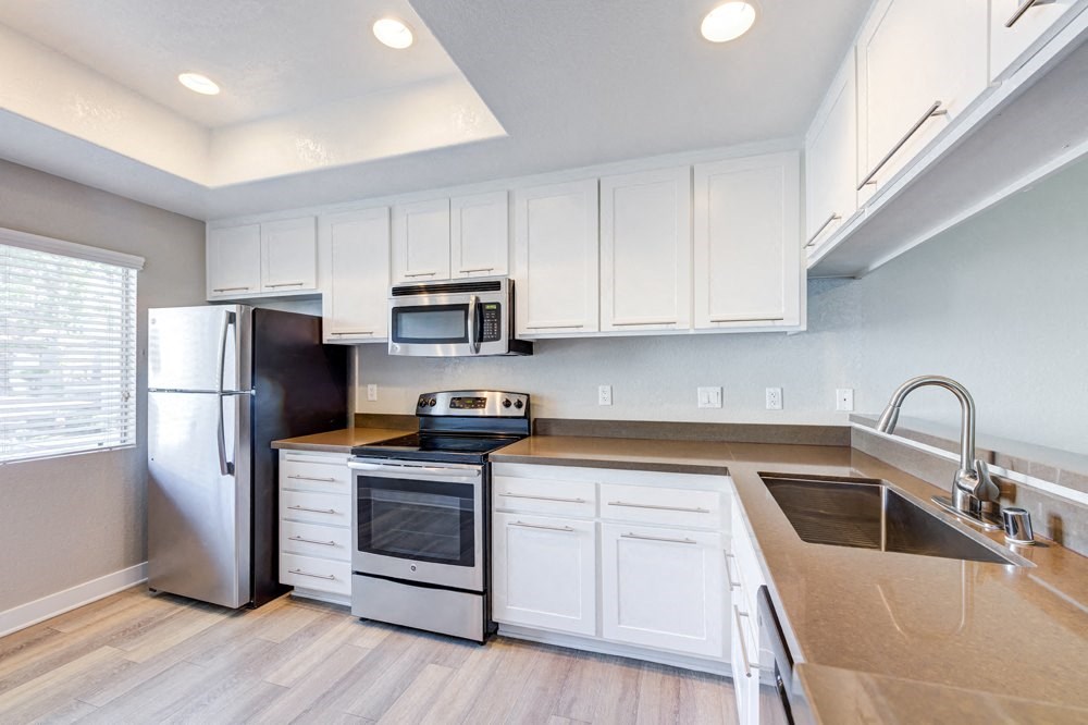 a kitchen with white cabinets and stainless steel appliances at Harbor Pointe, California