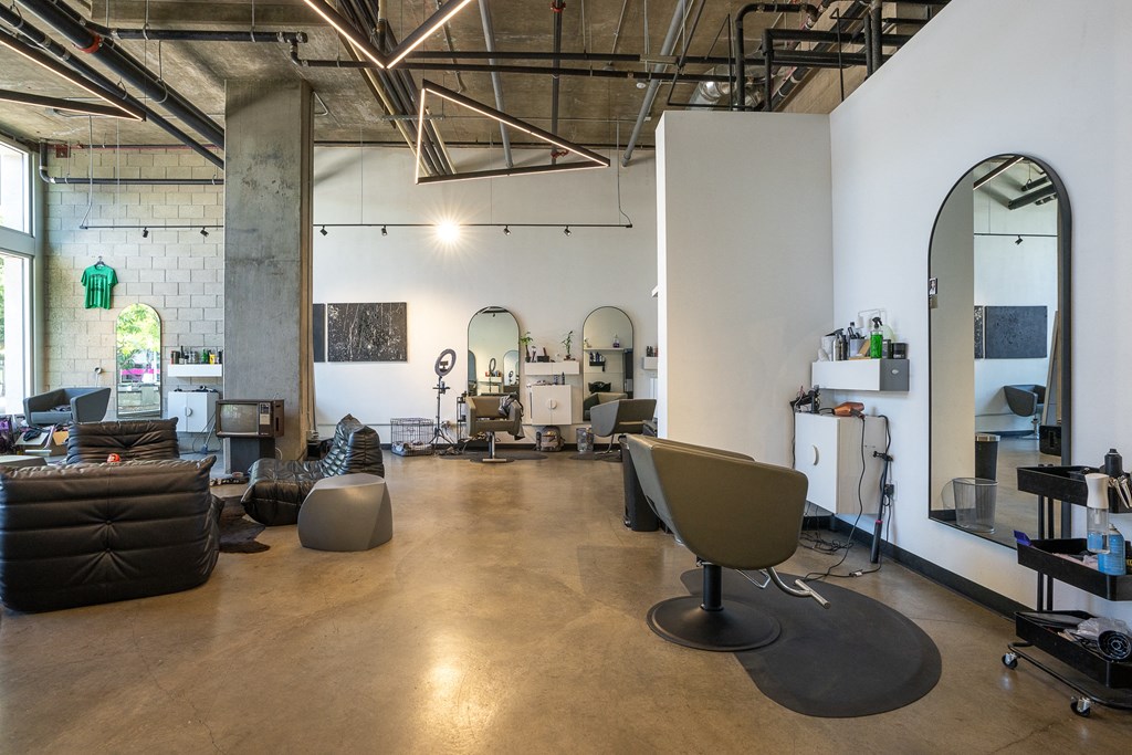Interior of neighborhood salon with seating area and salon chairs and mirror.