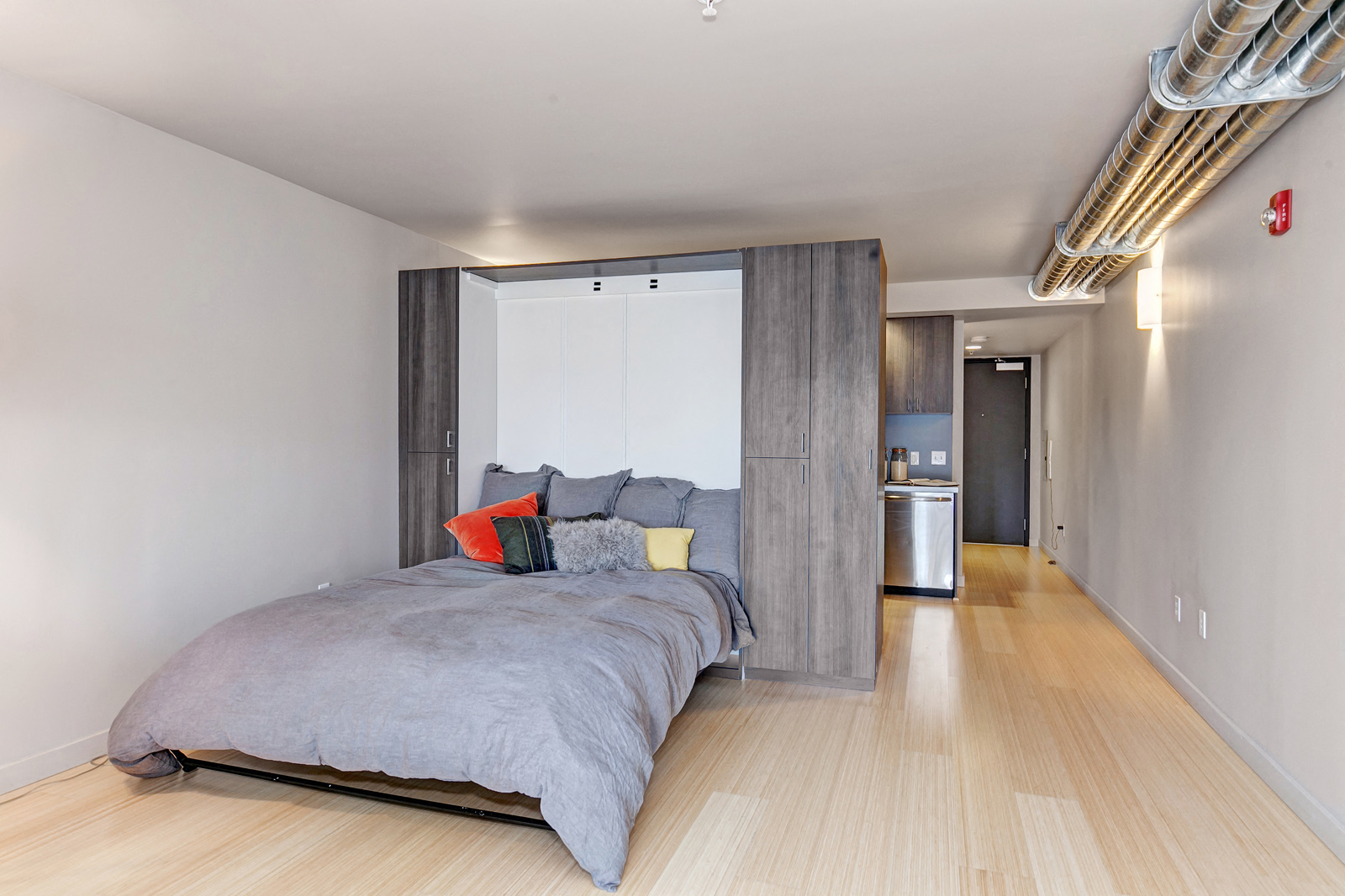 Lofts In Downtown Seattle - Studio Bedroom With Wood-Style Flooring and Bed With A Variety Of Pillows.