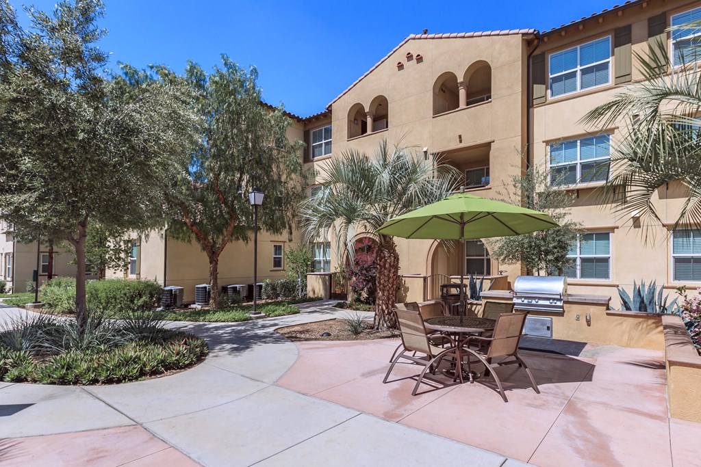 a patio with chairs and an umbrella in front of a building