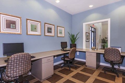 two desks and three chairs in our business center with a mirror and pictures on the wall