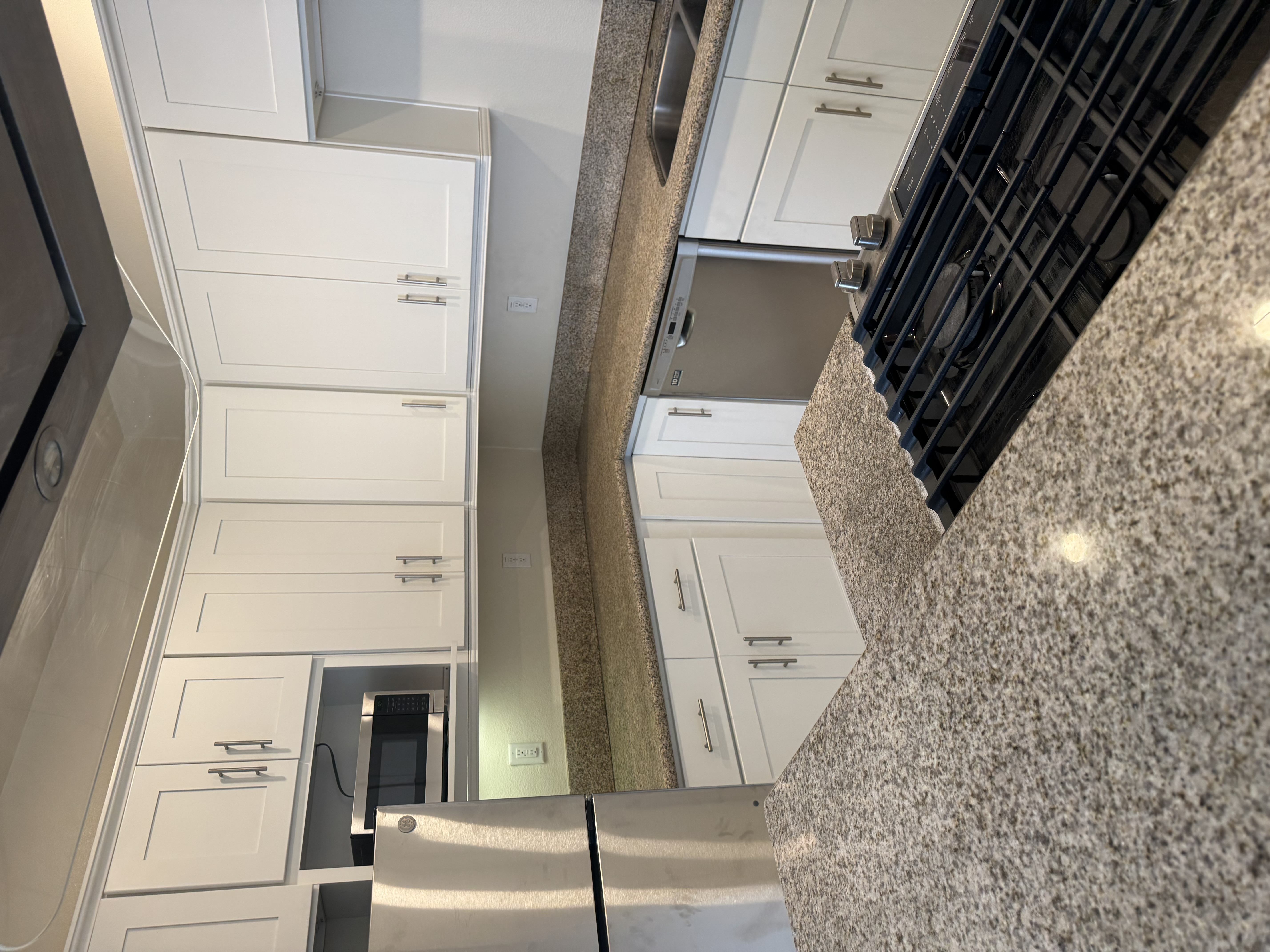 A kitchen with white cabinets and a counter top.