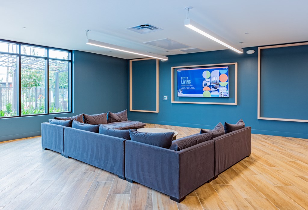 Sectional couch with large flat screen TV on wall.