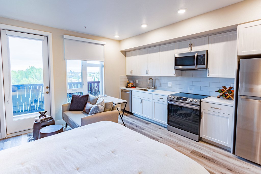 Sunnyvale Luxury Apartments - 1250 Lakeside - Open Floor Plan Kitchen With White Cabinetry, Wood-Style Flooring, Wood And Black Island, And Stainless Steel Appliances