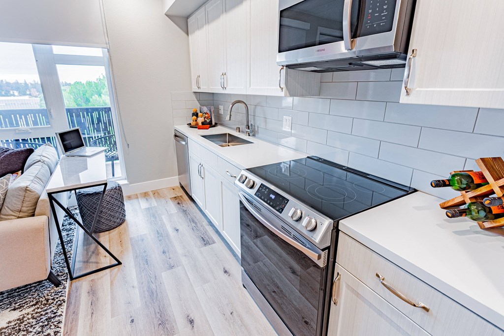 a kitchen with white cabinets and a black stove top oven and overhead microwave