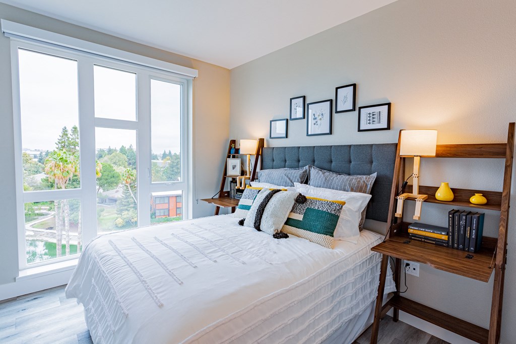 Two-Bedroom Apartments in Sunnyvale, CA - 1250 Lakeside - Bedroom with Plank Style Flooring, Bed, Floor-to-Ceiling Windows, and Nightstands with Lamps