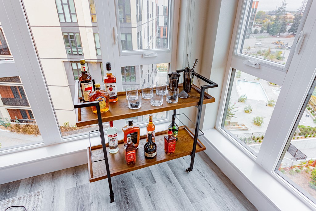 Bar cart in room with large windows and wood flooring.