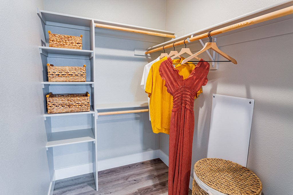 Walk in closet with shelves and baskets and clothes handing