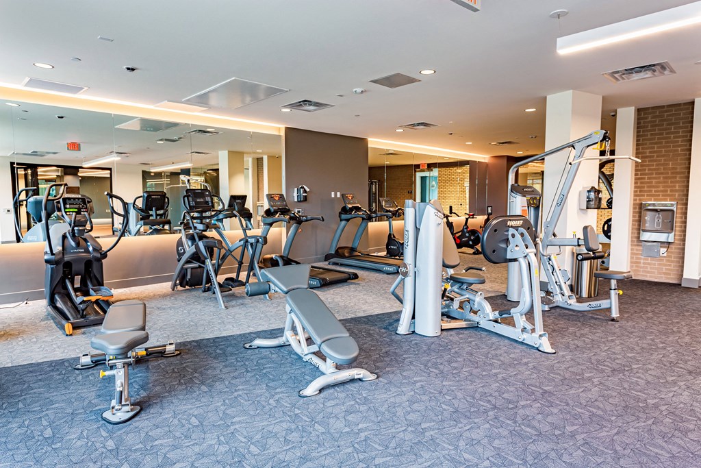 Sunnyvale Apartments in California - 1250 Lakeside - Fitness Center with Free Weights, Bench Press, Cardio Equipment, Mirror Wall, and Bright Overhead Lighting