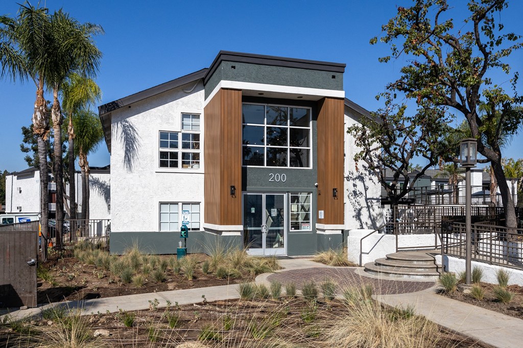 A modern building with a white facade and a brown door is surrounded by palm trees at Verandas Apartments, California