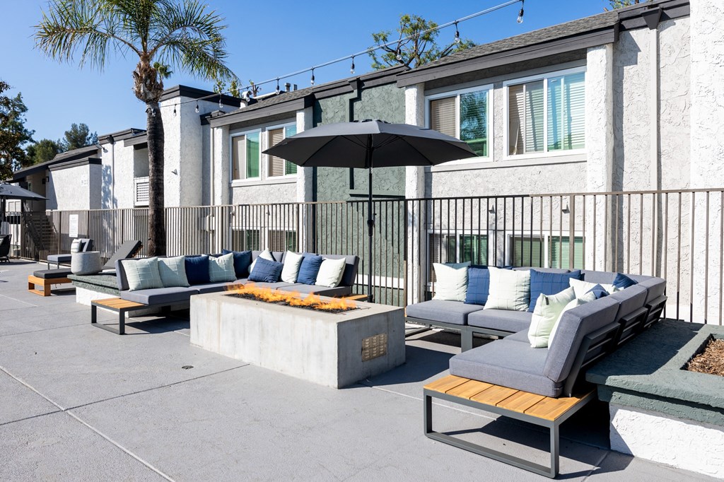A patio with a black umbrella and grey couches at Verandas Apartments, West Covina, CA, 91791