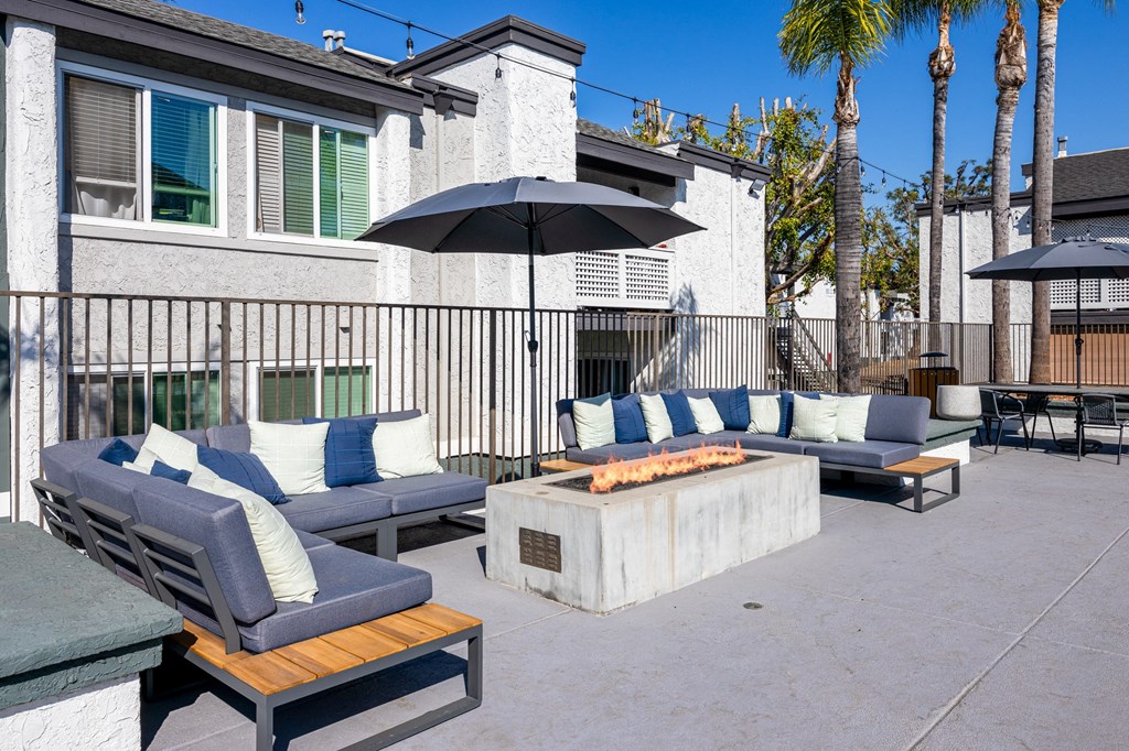A patio with a black umbrella and blue cushions at Verandas Apartments, West Covina, California