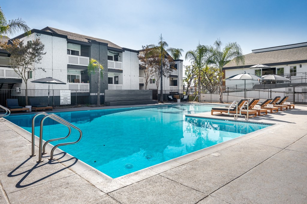 A swimming pool with a blue tinted water and sun loungers at Verandas Apartments, West Covina, 91791