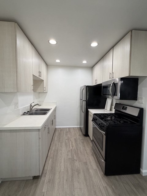 A kitchen with black appliances and white cabinets.