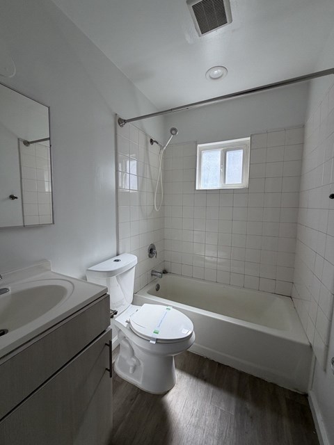 A white toilet in a bathroom with a white tub and sink.