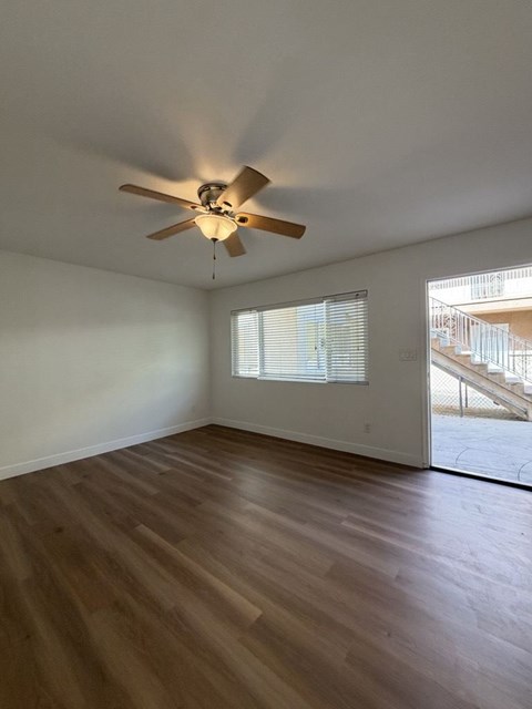 A room with a ceiling fan and wooden flooring.